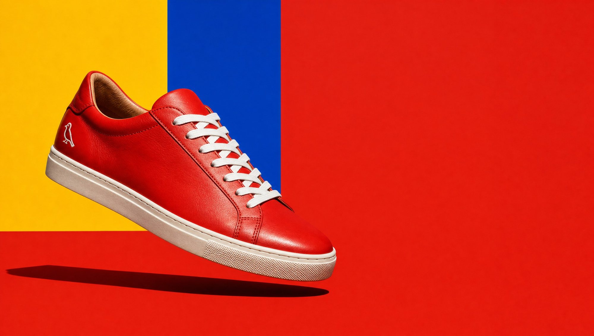 The Bellbird Low in Signal Red floating over red, yellow and blue colour blocks